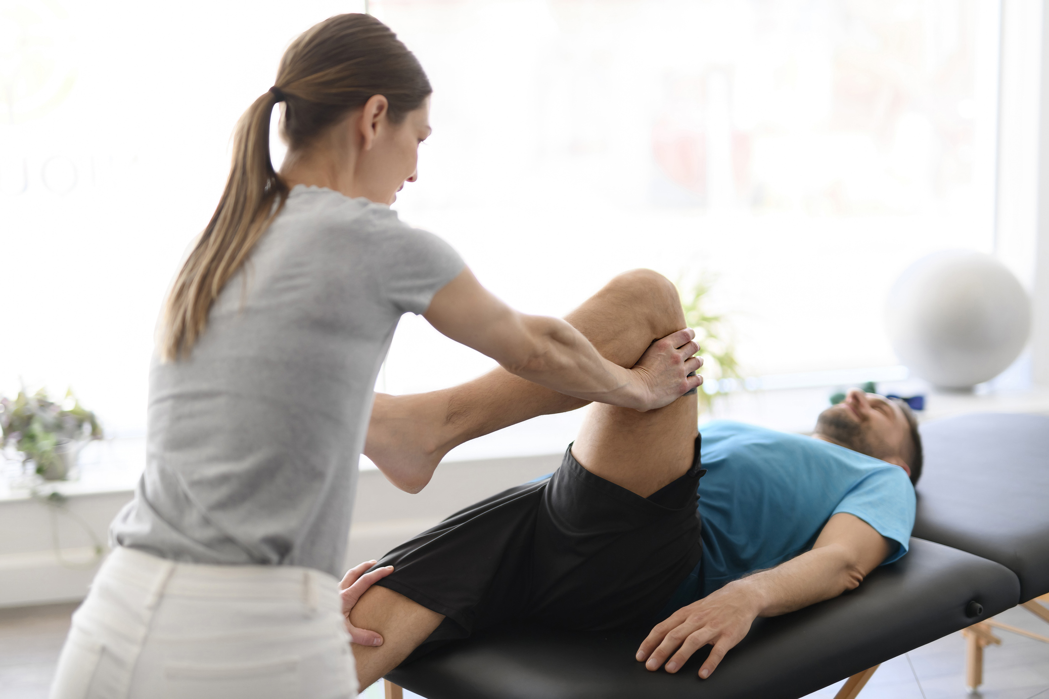 Modern rehabilitation physiotherapy woman worker with man client leg treatment